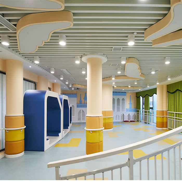 Pale green linear baffle ceiling in a colorful indoor kindergarten space