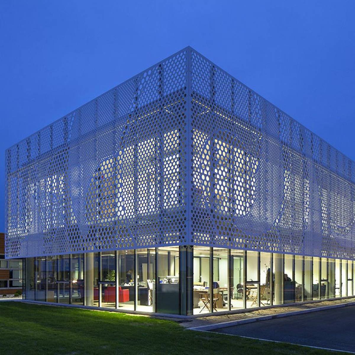 An illuminated perforated screen facade viewed from outside
