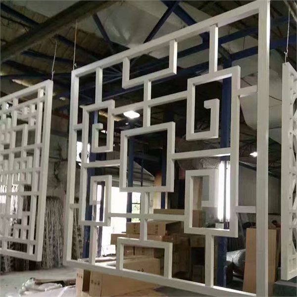 White open geometric aluminum grille panels displayed in a workshop